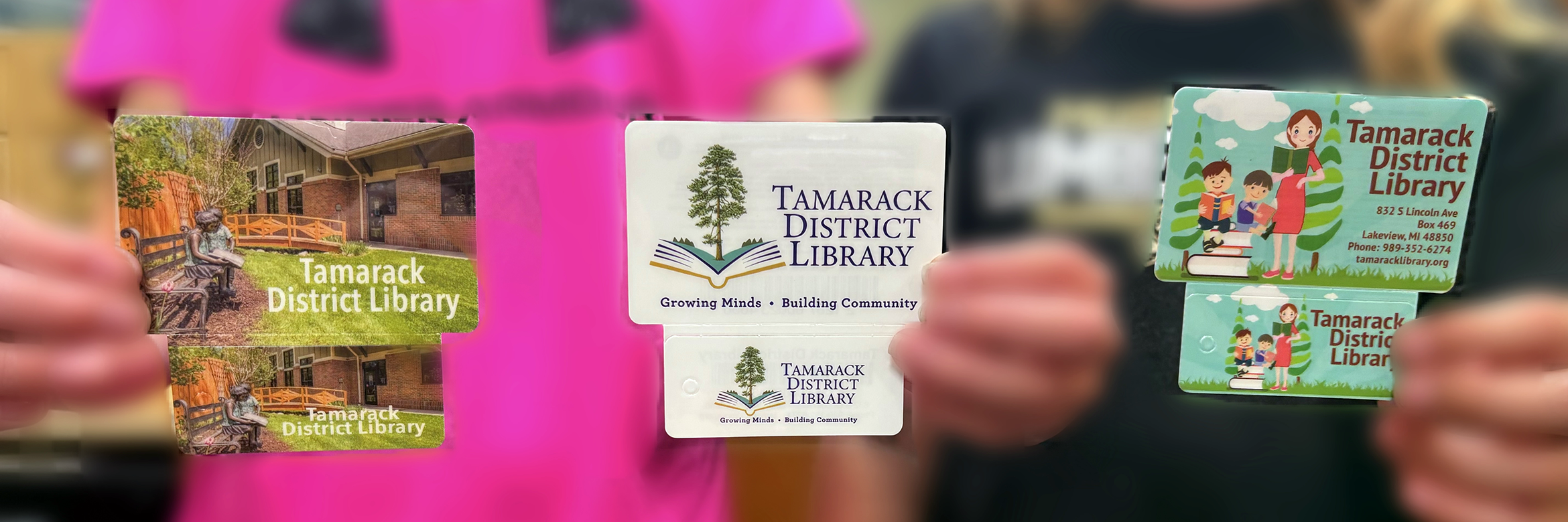 Two kids holding up different versions of the Tamarack District Library Cards