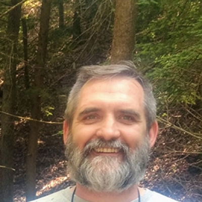 Man with a grey tshirt reading "Dad" with the outdoor woods in the background
