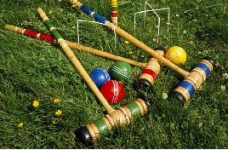 Croquet sticks and balls laying in the grass