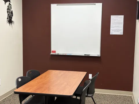 Small room with whiteboard and poster on one wall and small table and chairs in the middle