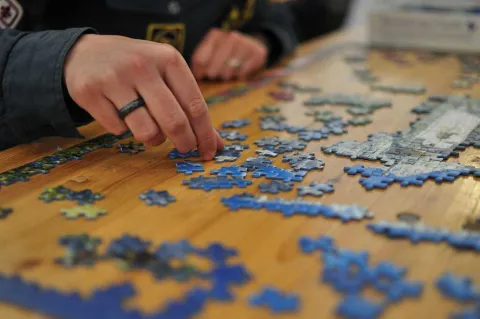Hands of a person putting together a jigsaw puzzle.