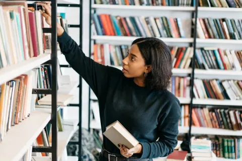 Librarian looking at books on the shelf at a library