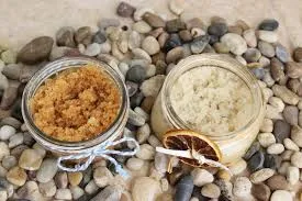 Jars of sugar scrub on small pebbles 