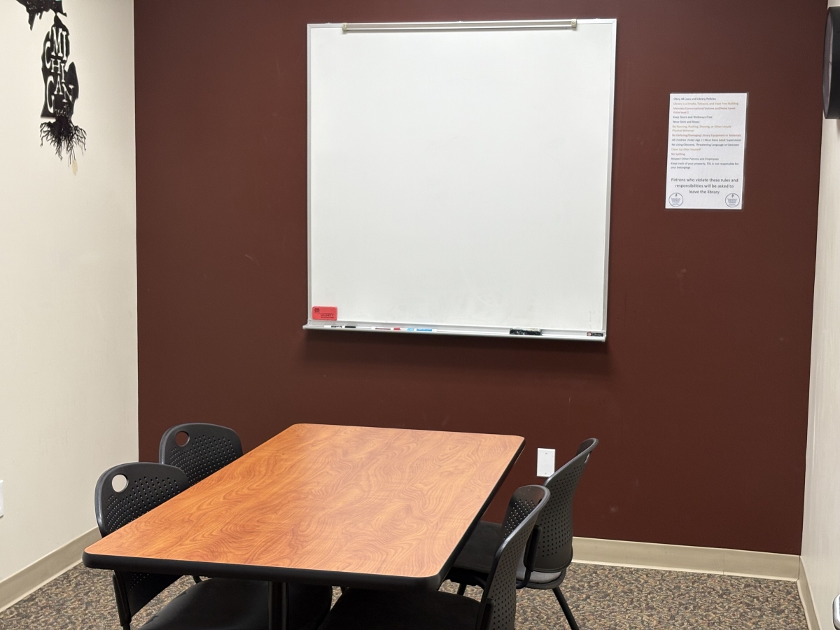 Small room with whiteboard and poster on one wall and small table and chairs in the middle