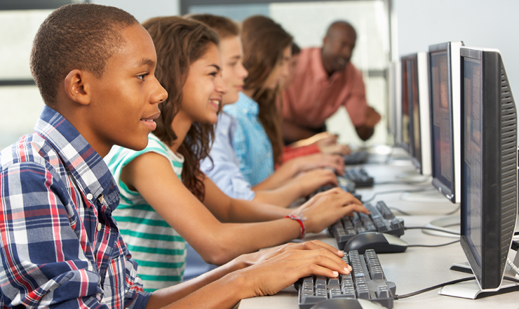 Group of teens sitting at computers in a computer lab